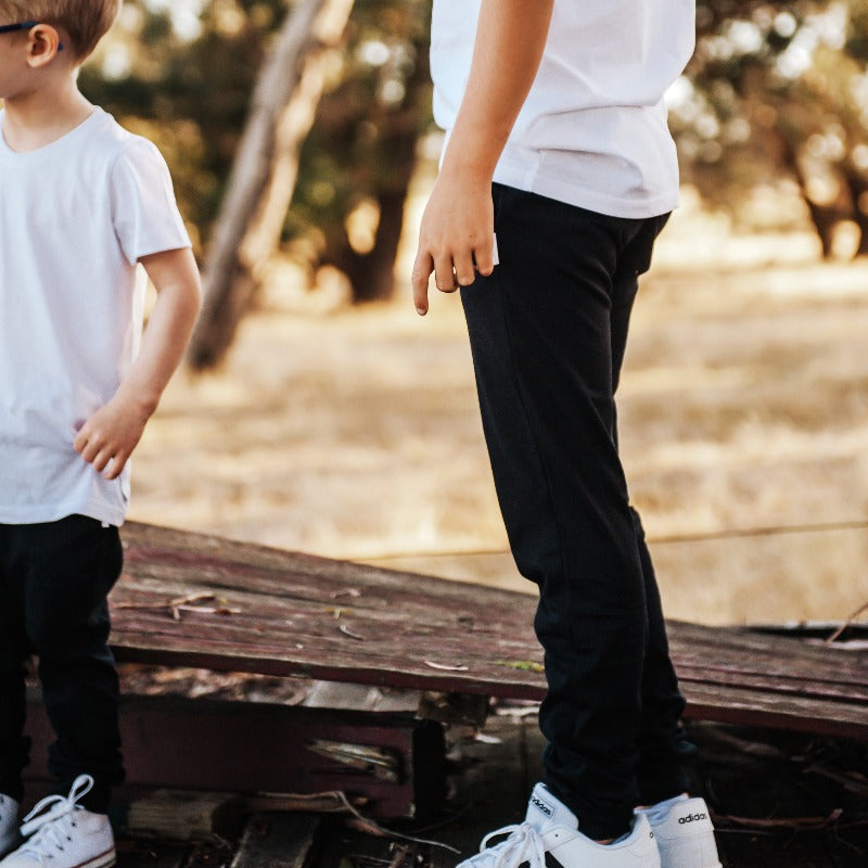 Black rye pants being worn by young boy with white t-shirt