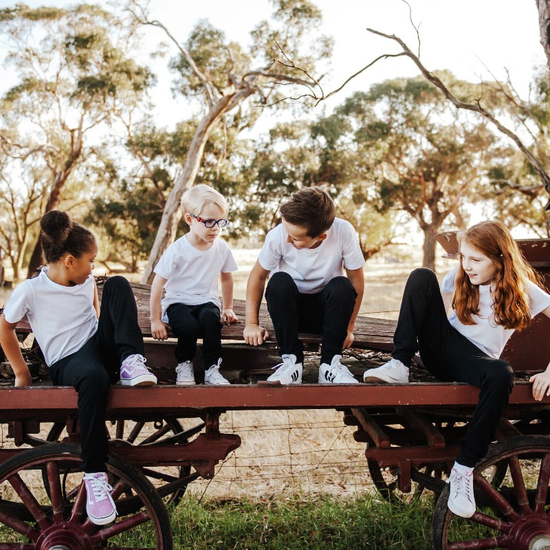 boys and girls sitting on an old wagon wearing black rye pants and white t-shits