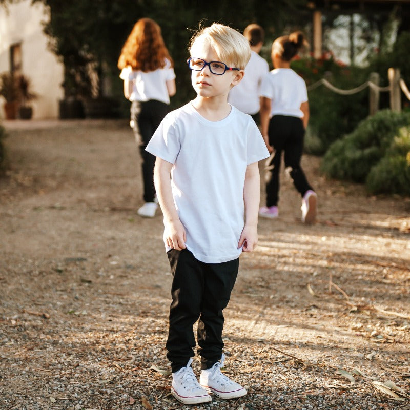 little boys standing looking into the distance wearing black rye pants and white t-shirt